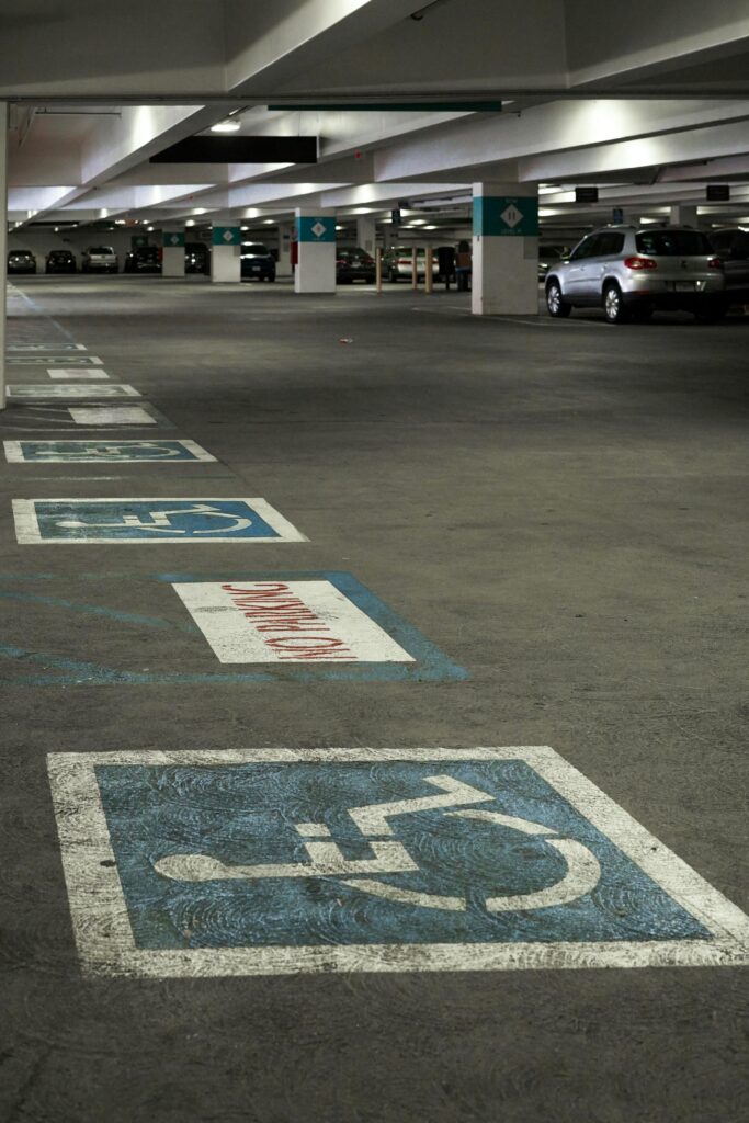 View of an underground parking lot featuring disabled parking spaces marked with blue pictographs.